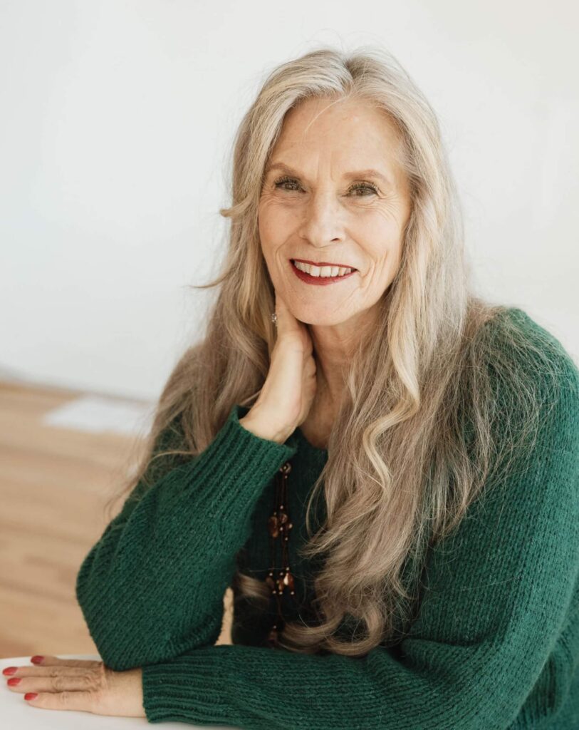 Bonnie Serratore smiling in a green sweater, seated at a table