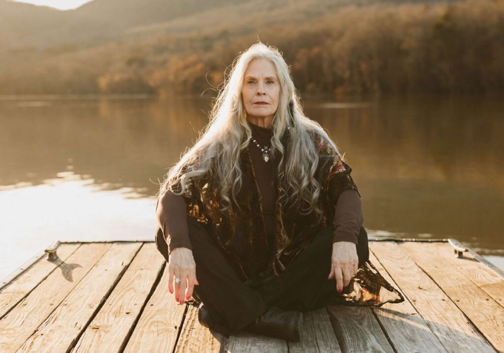 Energy Healer Bonnie Serratore in meditation pose on a dock at sunset