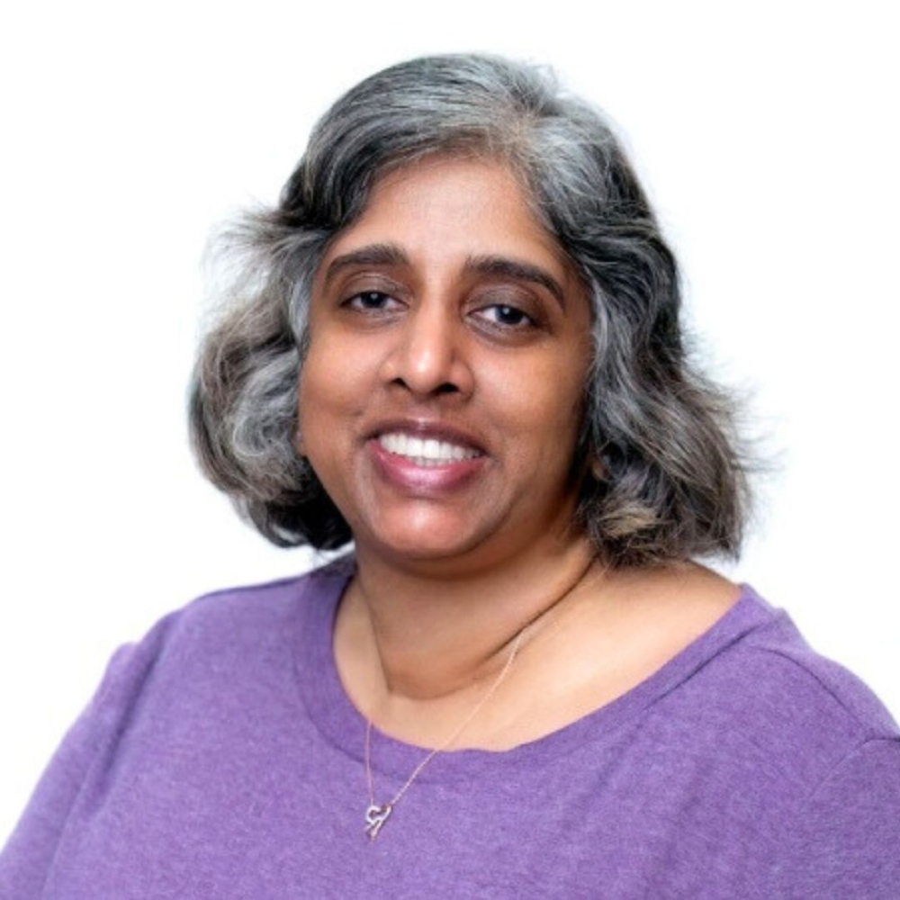 Saroja, team member, smiling in a purple shirt